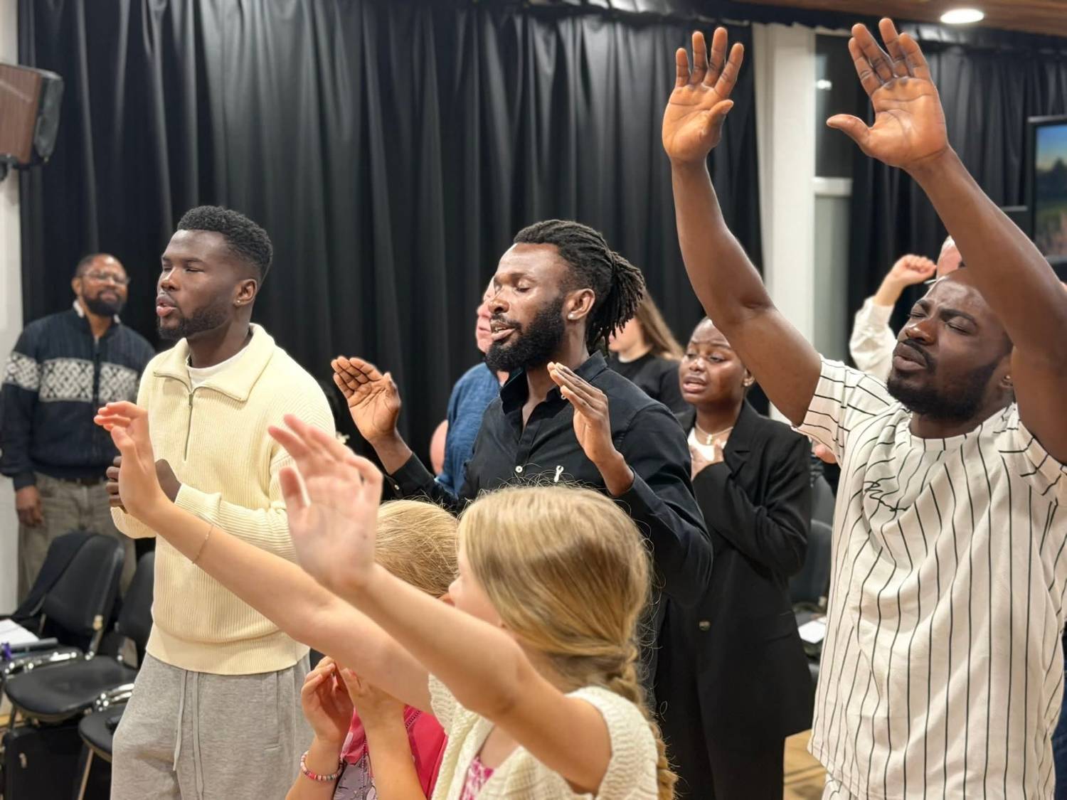 Congregation raising hands in worship at EBM